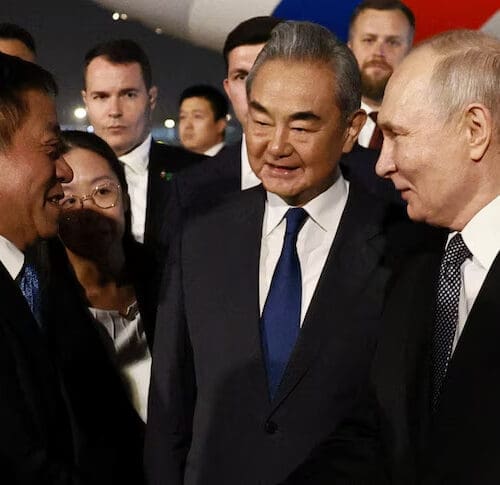 Russian President Vladimir Putin greets Chinese officials, including Foreign Minister Wang Yi after he landed in Beijing.