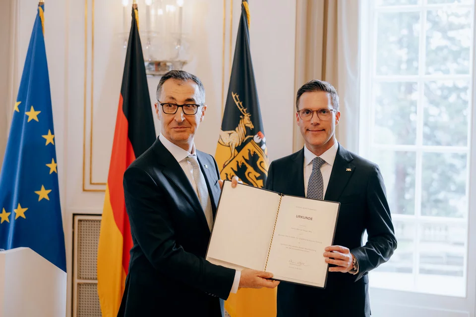 Green Minister President of Baden-Württemberg Cem Özdemir hands Baden-Württemberg's Deputy Minister President Manuel Hagel (right, CDU) his letter of appointment in Stuttgart, Germany.